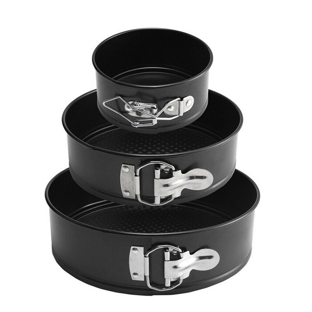 Set of three black springform pans with metal clamps on a white background