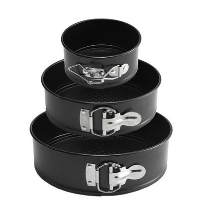 Set of three black springform pans with metal clamps on a white background