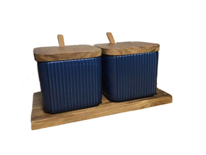 Two blue ceramic containers with wooden lids on a wooden stand against a white background