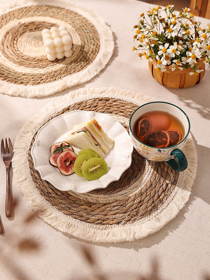 Tea cup with fruit platter on woven placemat with flowers in the background