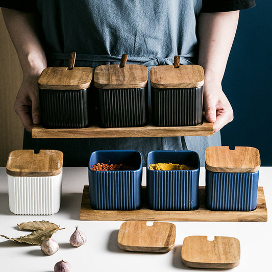 Person holding a tray with kitchen storage containers featuring wooden lids.