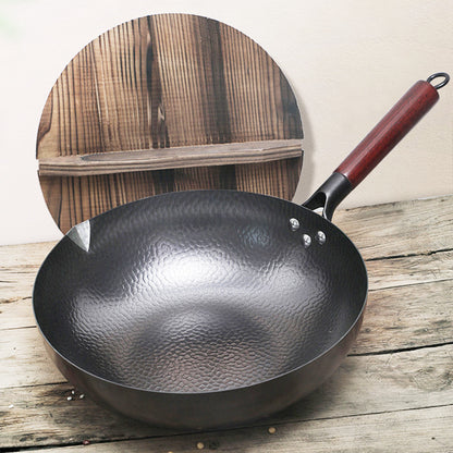 Black wok with a red handle on a wooden surface