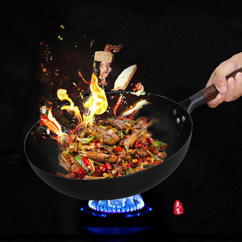 Wok with food being cooked over a flame on a black background