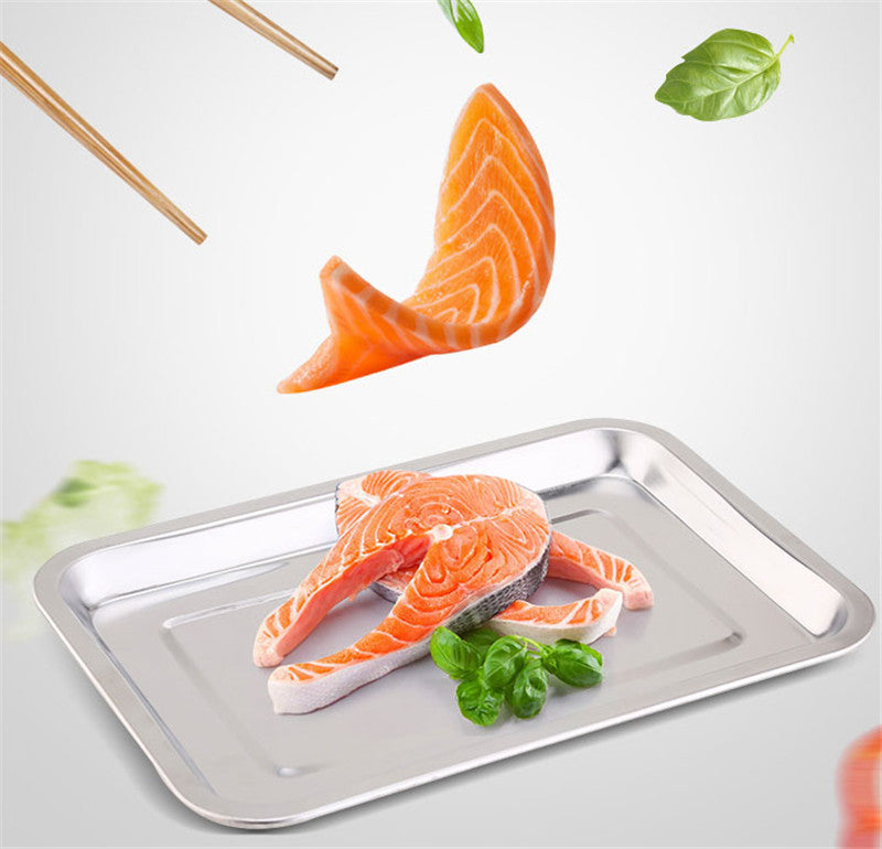 Raw salmon fillets on a metal tray with basil leaves on a light gray background